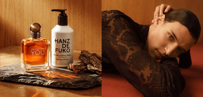 Eau de Cologne et crème à raser sur une surface en pierre à côté d'un homme en haut en dentelle appuyé sur son bras contre un fond marron.