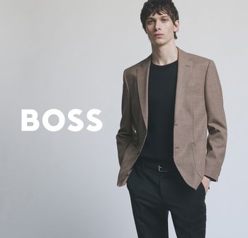 Blazer à carreaux marron avec une coupe ajustée, associé à un t-shirt noir à col rond. Le modèle se tient les mains dans les poches, sur un fond clair.