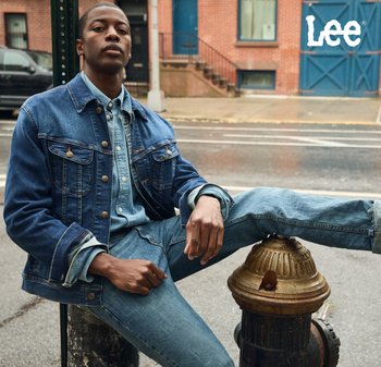 Mörkblå jeansjacka med metalldetaljer, lager-på-lager över en ljusblå jeansskjorta, kombinerad med matchande jeans, sittande på en brandpost.