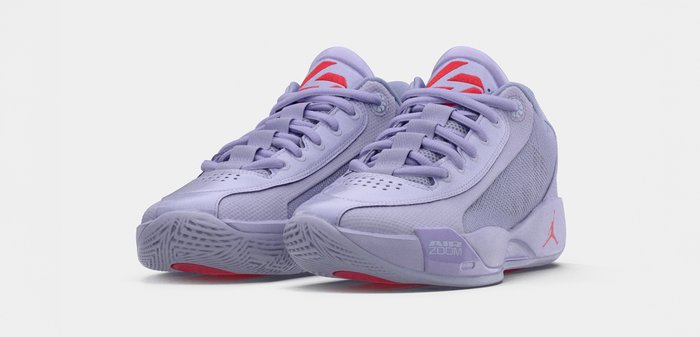 Μωβ αθλητικά παπούτσια Air Jordan χαμηλού ύψους με κόκκινα στοιχεία, διχτυωτές πλαϊνές επιφάνειες και σχέδιο με κορδόνια, τοποθετημένα σε γωνία πάνω σε λευκό φόντο.