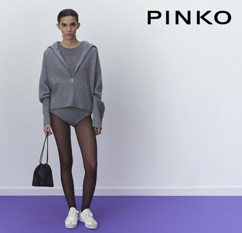 Sudadera de punto gris con acentos verdes, combinada con un bodysuit gris y medias negras transparentes. Un bolso negro y zapatillas blancas completan el look.