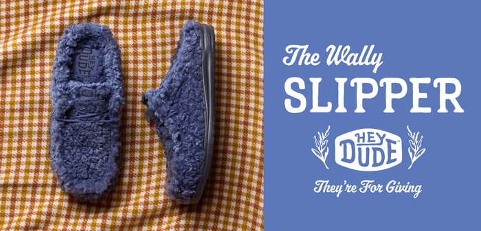 Chaussons en velours bleu, sur un tissu à carreaux jaune et blanc, avec la marque "The Wally Slipper" et son slogan de Hey Dude.