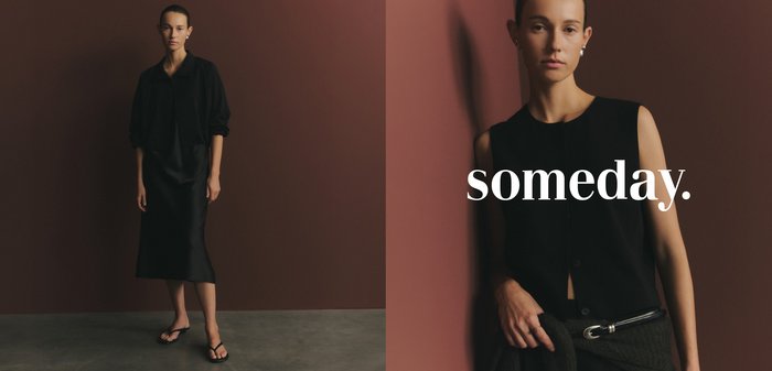 Jeune femme portant un haut noir sans manches et des boucles d'oreilles en perles, debout contre un mur marron avec le mot "someday" sur sa poitrine.