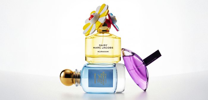 Trois flacons de parfum empilés : Daisy Marc Jacobs jaune avec un bouchon floral, Gentle Fluidity bleu, et Giorgio Armani Sì violet incliné.
