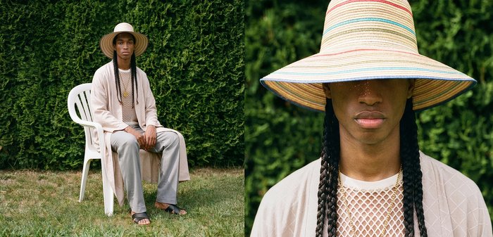 Personne avec de longues tresses porte un chapeau rayé à large bord, un cardigan clair et une chemise en maille, assise sur une chaise blanche dans un jardin vert.