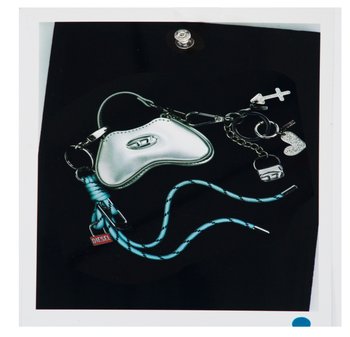 Portachiavi a forma di cuore in argento con cordino blu, etichetta con logo Diesel, croce, cuore scintillante e mini portachiavi a forma di borsa su sfondo nero.