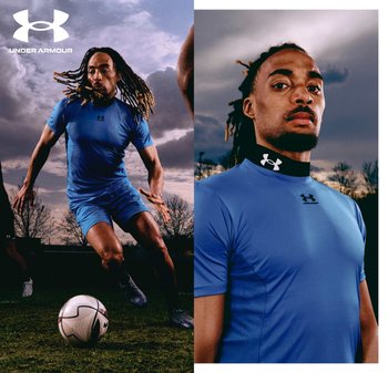 Athlete with dreadlocks in blue Under Armour sportswear controlling soccer ball outdoors under cloudy sky.