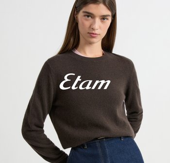Brązowy sweter z okrągłym dekoltem wykonany z miękkiego materiału, z dużym białym logo „Etam” na całej szerokości klatki piersiowej. Dopasowane długie rękawy, luźny fason.