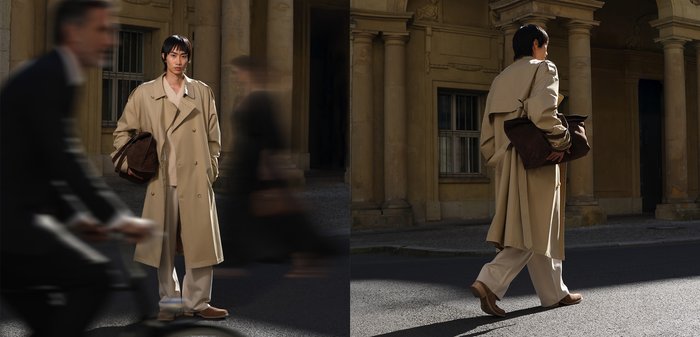 Manteau beige, pantalon crème à jambes larges, sac marron. Le modèle se tient dans la rue, avec des colonnes ensoleillées en arrière-plan. Textures de tissu douces visibles.