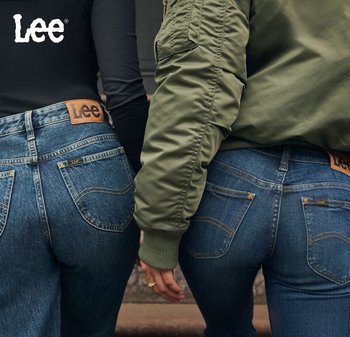 Deux personnes se tenant côte à côte, portant des jeans en denim de finition bleue, avec des étiquettes en cuir marron et des détails de couture visibles.