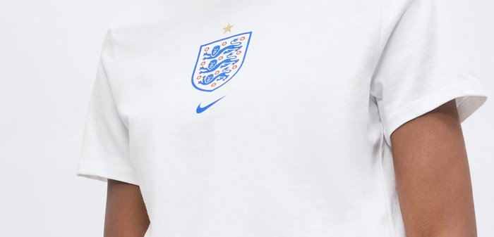 Maillot de sport blanc avec l'écusson de football de l'Angleterre comportant trois lions bleus et une étoile dorée au-dessus, accompagné d'un swoosh Nike bleu en dessous.