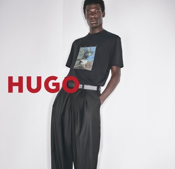 Schwarzes T-Shirt mit kurzen Ärmeln und grafischem Druck auf der Vorderseite, kombiniert mit locker sitzenden schwarzen Hosen und einem Gürtel mit rechteckiger Schnalle.