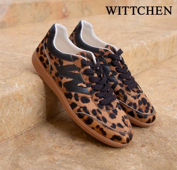 Paar Leopardenmuster-Sneaker mit schwarzen Schnürsenkeln, schwarzen Akzenten und Gummisohlen, die auf beigen Steinstufen liegen, Marke WITTCHEN.