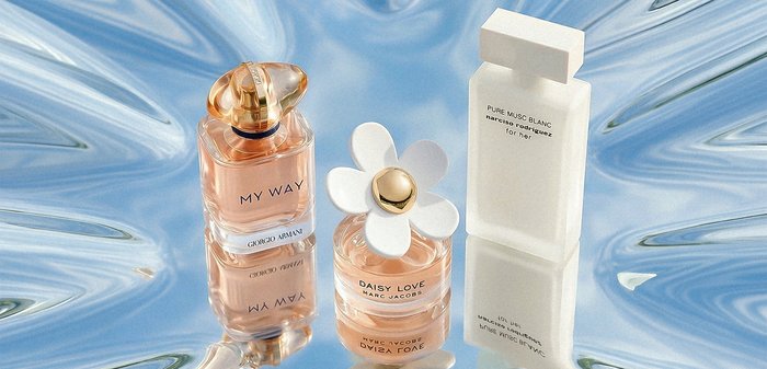 Trois flacons de parfum — My Way de Giorgio Armani, Daisy Love de Marc Jacobs et Pure Musc Blanc de Narciso Rodriguez — sur une surface bleue réfléchissante.