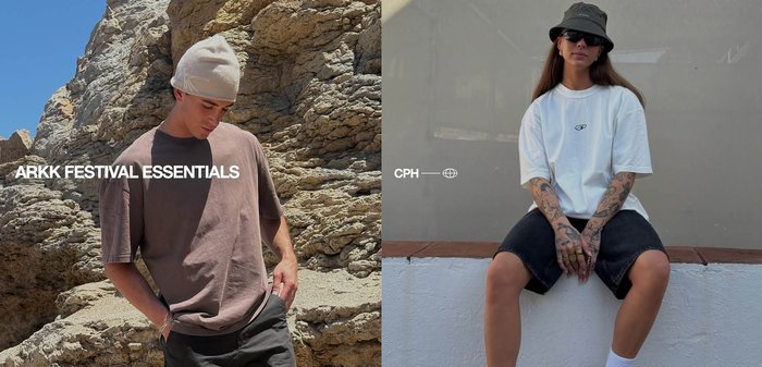 Mand i brun t-shirt og beige beanie står ved en klippevæg, kvinde med tatoveringer har hvid t-shirt, sorte shorts, bøllehat og solbriller på, sidder på en kant.
