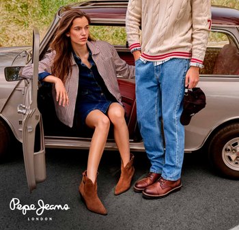 Botas de ante marrón hasta el tobillo, vestido de mezclilla, chaqueta a rayas, suéter de punto beige, jeans azules y un coche vintage en el fondo.