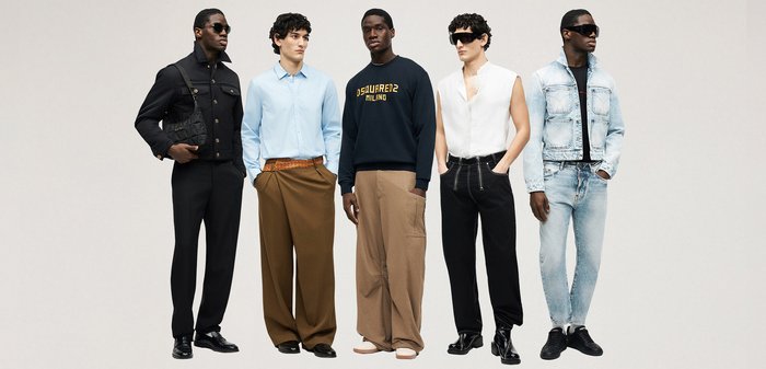 Cinq hommes sont alignés portant des tenues stylées variées comprenant une veste noire, une chemise bleue avec un pantalon marron, un sweat-shirt bleu marine, un haut blanc sans manches, et une veste en denim claire avec un jean.