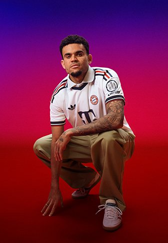 Mann mit Tattoos, der ein weißes Sporttrikot und beige Hose trägt, hockt auf einem Knie vor einem violett-roten Farbverlauf-Hintergrund.