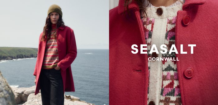 Červený vlněný kabát s kulatými knoflíky, přes barevně vzorovaný svetr v krémové, růžové a zelené barvě. Modelka nosí olivově zelenou pletenou čepici.