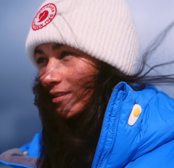 Blauer Puffermantel mit einer strukturierten grauen Innenausstattung, ausgestattet mit gelben und weißen Hardware-Akzenten; weiße Strickmütze mit rotem Logo.