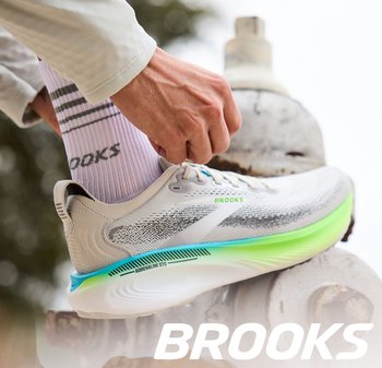 Lichtgewicht hardloopschoen in het wit met een gestructureerd bovenwerk, gekleurde accenten in blauw en groen, en een uitgesproken gebogen zool.