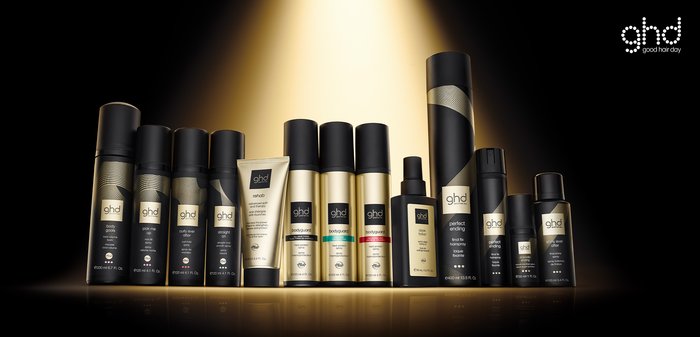 A collection of GHD hair care products featuring black and gold packaging in various shapes and sizes, prominently displayed against a dark background.