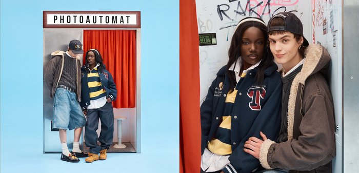 Deux jeunes portant des vêtements décontractés urbains se tiennent près d'une cabine photo rétro avec un rideau rouge et une enseigne "PHOTOAUTOMAT".