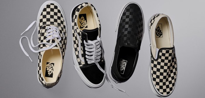 Sneakers in tela a scacchi bianco e nero, disponibili in modelli con lacci e senza lacci, con suole in gomma bianca e branding.