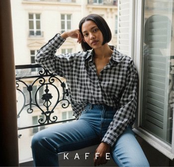 Zwart-wit geruit overhemd over denim jeans. Zachte stof, losse pasvorm en knoopsluiting. Natuurlijk licht van een raam accentueert de texturen.