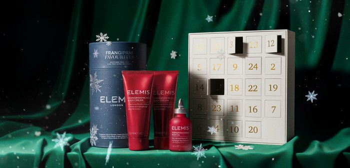 Sett inkluderer en blå sylinderformet beholder og tre røde rør. Bemerkelsesverdige detaljer er gullskrift, en liten glassflaske og en adventskalender.