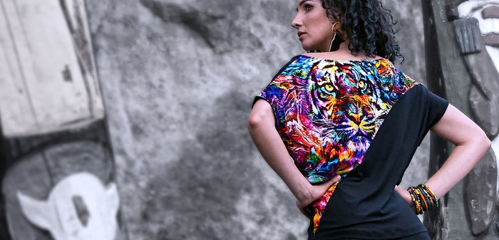 Kort mouwshirt met een zwarte stofbasis en een levendige, multicolor tijgerafbeelding aan één kant. Losse pasvorm met een brede halslijn.