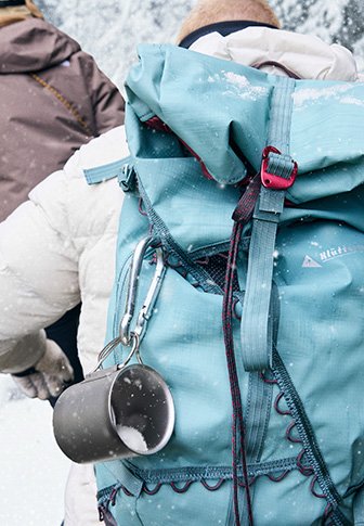 Τσάντα πλάτης σε τυρκουάζ χρώμα, κατασκευασμένη από ανθεκτικό υλικό, με κλείσιμο κορδονιού, εξωτερικούς βρόχους και ένα μεταλλικό κύπελλο προσαρτημένο στο πλάι.