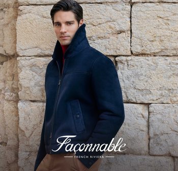 Veste en suedine marine avec col montant et fermeture éclair, dotée de poches latérales et d'une texture lisse, sur fond de mur en pierre.