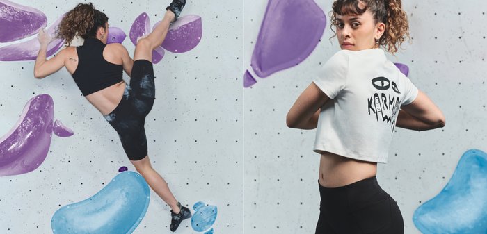 Μαύρο αμάνικο τοπ και μαύρο σορτς με ψηλή μέση και υφή. Πολύχρωμες λαβές αναρρίχησης σε γκρι τοίχο, συμπεριλαμβανομένων μοβ και μπλε σχημάτων.