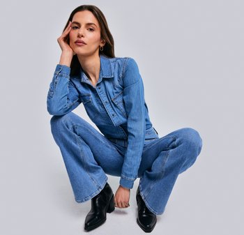 Denim aantal in lichtblauw met lange mouwen, drukknopen, twee borstzakken en uitlopende benen. Gecombineerd met zwarte enkellaarsjes.