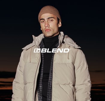 Mann trägt beige Steppjacke, schwarzen Rollkragenpullover und braune Mütze, steht vor dunklem Sonnenuntergangshimmel mit überlagertem "BLEND"-Logo.