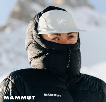 Schwarze isolierte Jacke mit hohem Kragen und Reißverschluss, mit dem "MAMMUT"-Logo. Eine hellfarbige Mütze wird auf dem Kopf getragen.