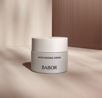 Crème hydratante dans un contenant rond blanc avec un couvercle assorti. Le texte en noir sur le devant indique "CRÈME HYDRATANTE" et "BABOR."