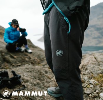Schwarze Outdoor-Hosen mit einem hellgrauen Mammut-Logo, akzentuiert mit einer blauen Zugkordel, aus strapazierfähigem Material, vor einem felsigen Hintergrund.