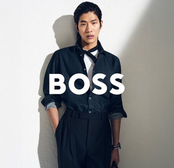 Camicia in denim scuro con bottoni e maniche arrotolate, abbinata a una t-shirt bianca e pantaloni neri a vita alta. Marchio ben visibile: "BOSS."