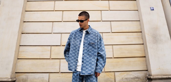 Zestaw kurtki i spodni dżinsowych z wzorem logo 'WB' w jasnoniebieskim kolorze. Pod spodem biała koszulka, noszona z ciemnymi okularami przeciwsłonecznymi.