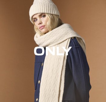 Beige gebreide beanie en sjaal met een ruitpatroon, gelaagd over een marineblauwe jas met gouden knopen en een gestructureerde kraag.