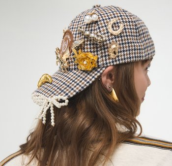 Houndstooth patterned cap with gold and pearl embellishments, featuring floral accents and decorative clips, in brown and beige tones.