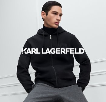 Sudadera con cremallera negra de tejido texturizado, con un parche de logo en el pecho y cordones en la capucha, llevada sobre un cuello de tortuga negro.