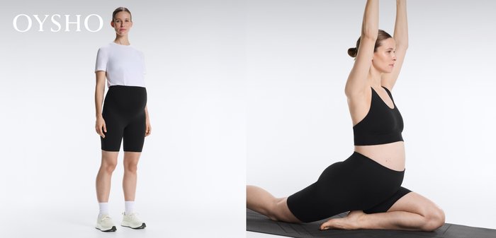 Pregnant woman in black sportswear performs a low lunge yoga pose on a mat with arms extended overhead.