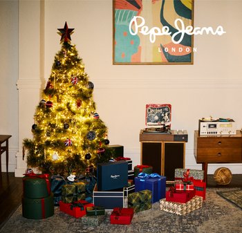 Decorated Christmas tree with lights and ornaments beside wrapped presents, vintage record player, and wooden furniture in a cozy room.