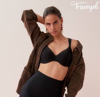 Soutien-gorge nero in tessuto morbido e spalline larghe, indossato sotto un cappotto marrone con stampa leopardata. La modella posa con una mano sul collo.