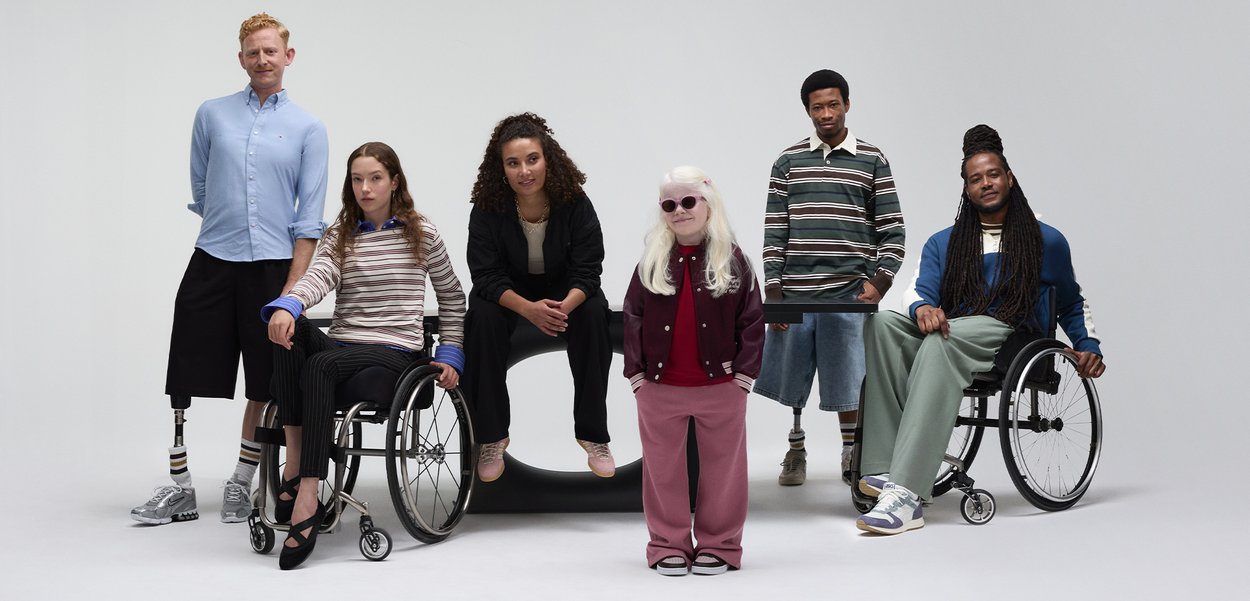 Šest posameznikov, vključno z dvema v invalidskih vozičkih, nosi raznolike obleke: casual srajce, puloverje in hlače v različnih barvah in teksturah.