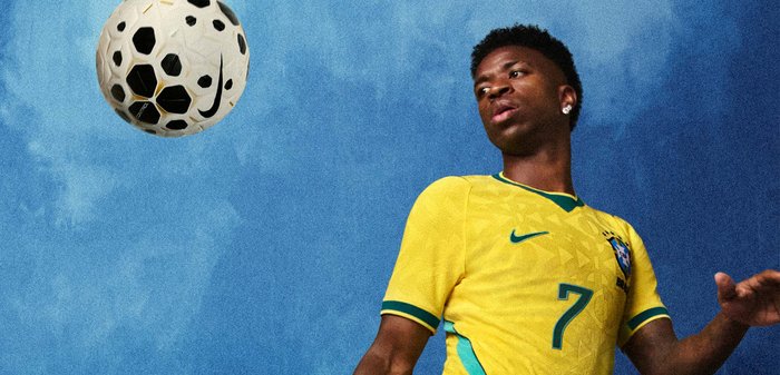 Νέος άνδρας ποδοσφαιριστής με κίτρινη φανέλα με αριθμό 7 κοιτάζει μια μπάλα που αιωρείται στον αέρα με φόντο τον μπλε ουρανό.