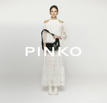 White lace dress with long sleeves and cut-out shoulders, paired with a black leather handbag and white heeled boots. Minimalist background.